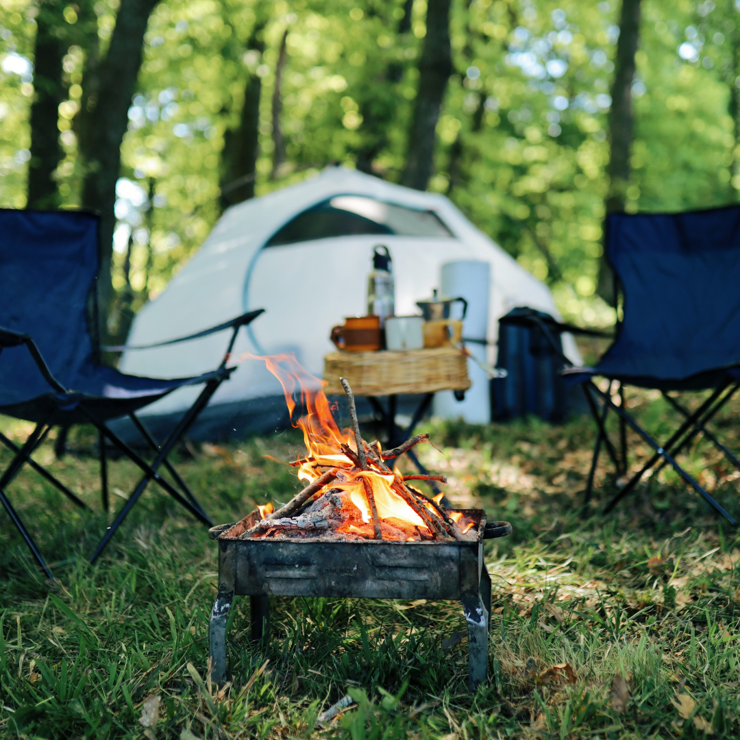Portable campfire stove with camping chairs and tent setup for outdoor cooking and survival gear.