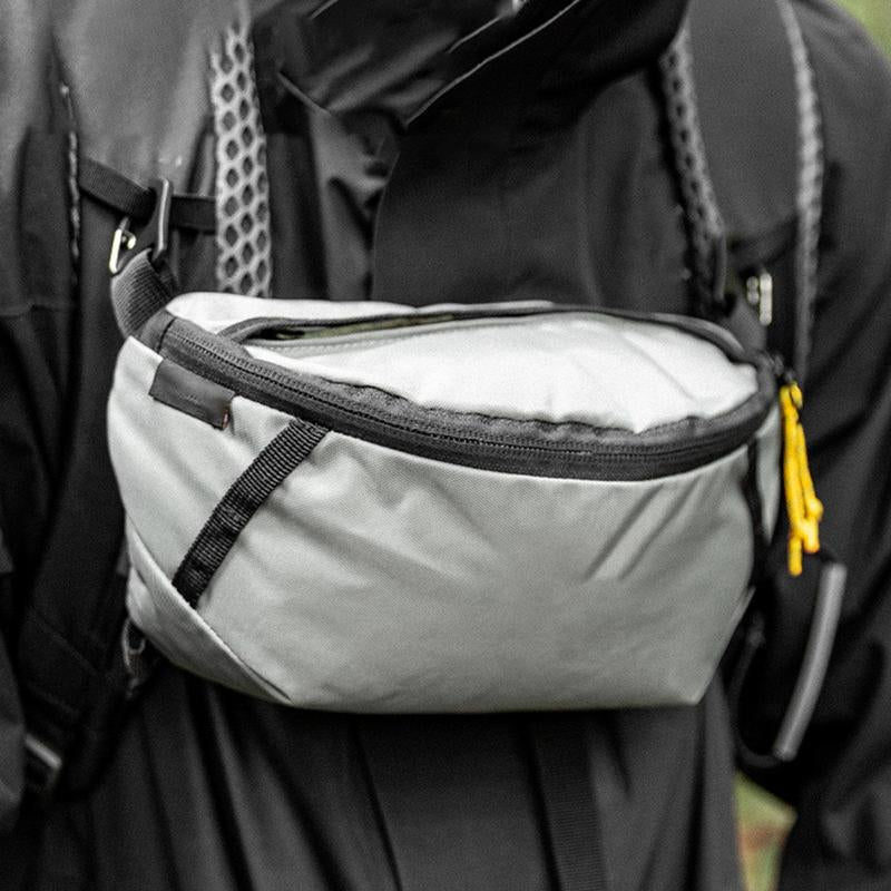 Person wearing a backpack with a gray waist bag attached
