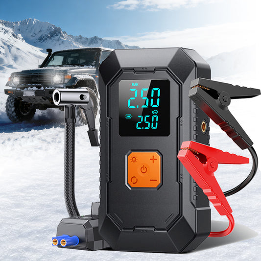 Car jump starter with digital display in a snowy landscape with a vehicle.