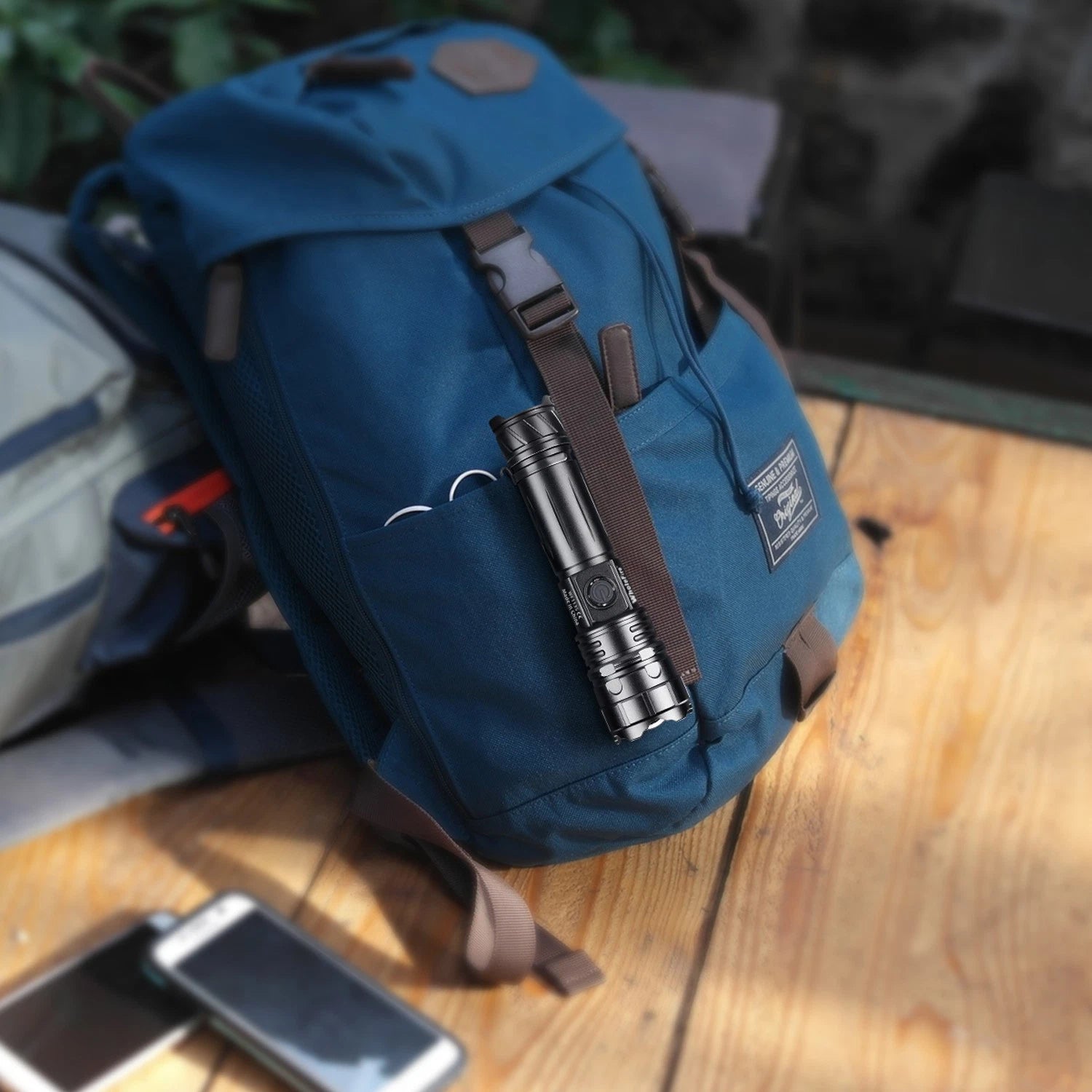 Blue backpack with a flashlight on a wooden surface
