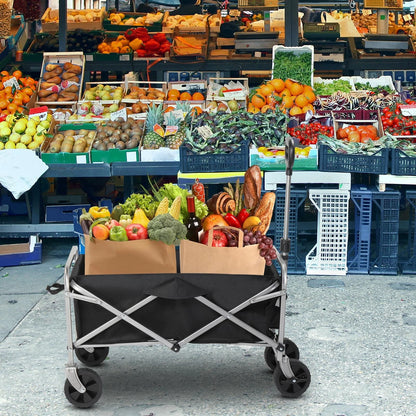 Cart filled with groceries in front of a market stall with various fruits and vegetables.