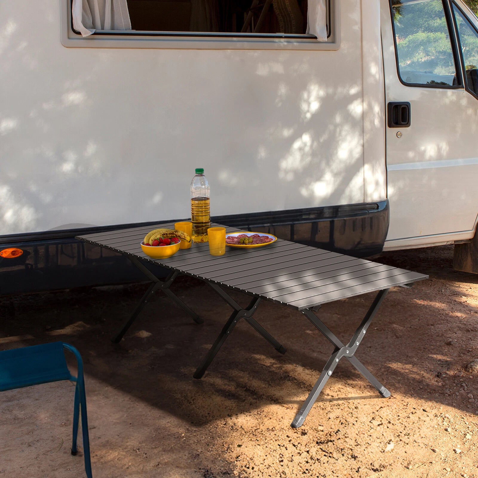 Portable folding table set up outdoors next to a white van with food and drinks on it.