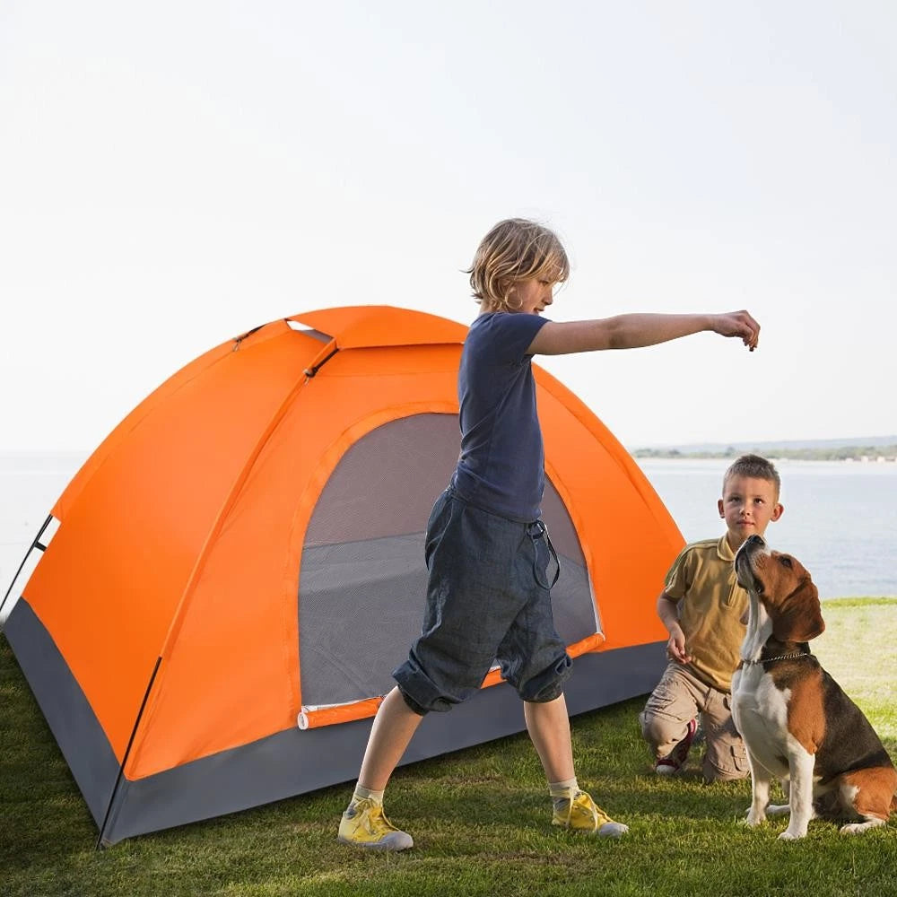 Two children and a dog standing near an orange and gray tent outdoors.