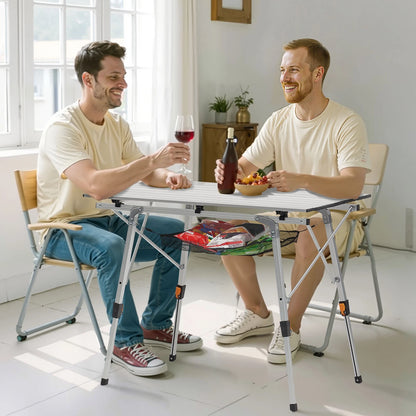 Two men sitting at a small table indoors, one holding a glass of red wine and the other a bottle.